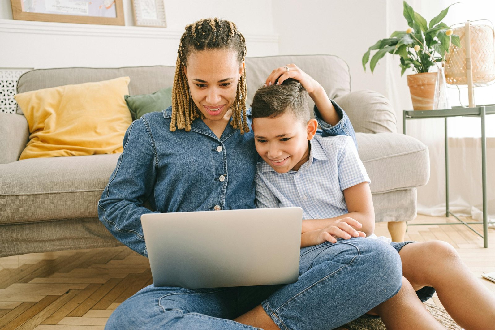 A loving mother and her son enjoying a fun time together while using a laptop indoors.